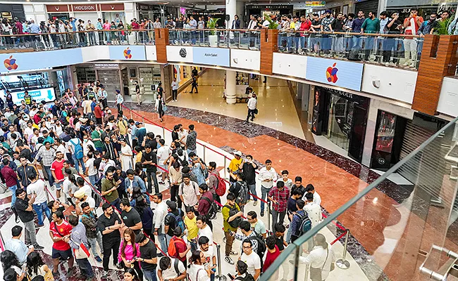 Customers wait in line outside the Apple store in New Delhi - Sakshi