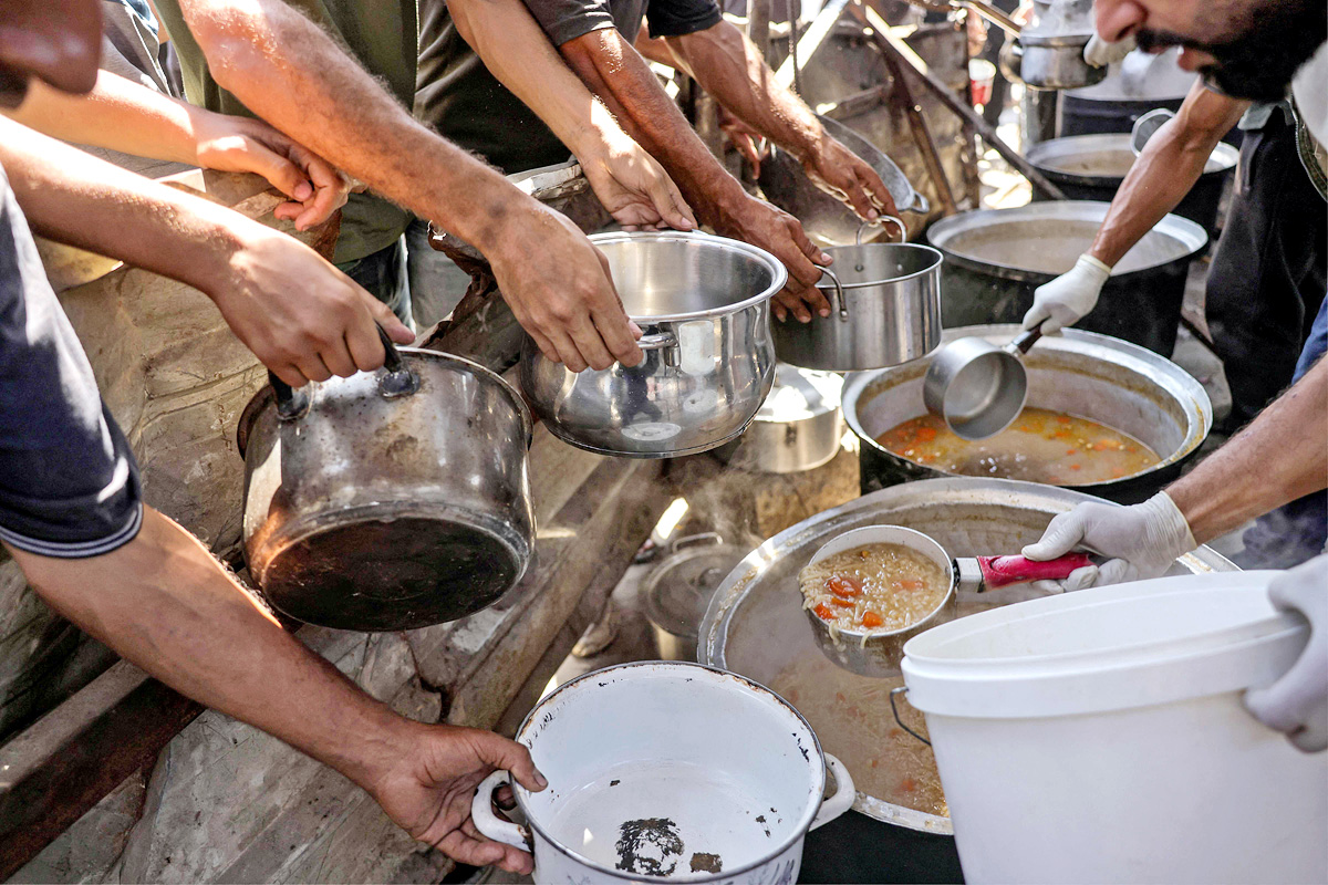 Palestinians wait for donated food at a community kitchen in Gaza City20