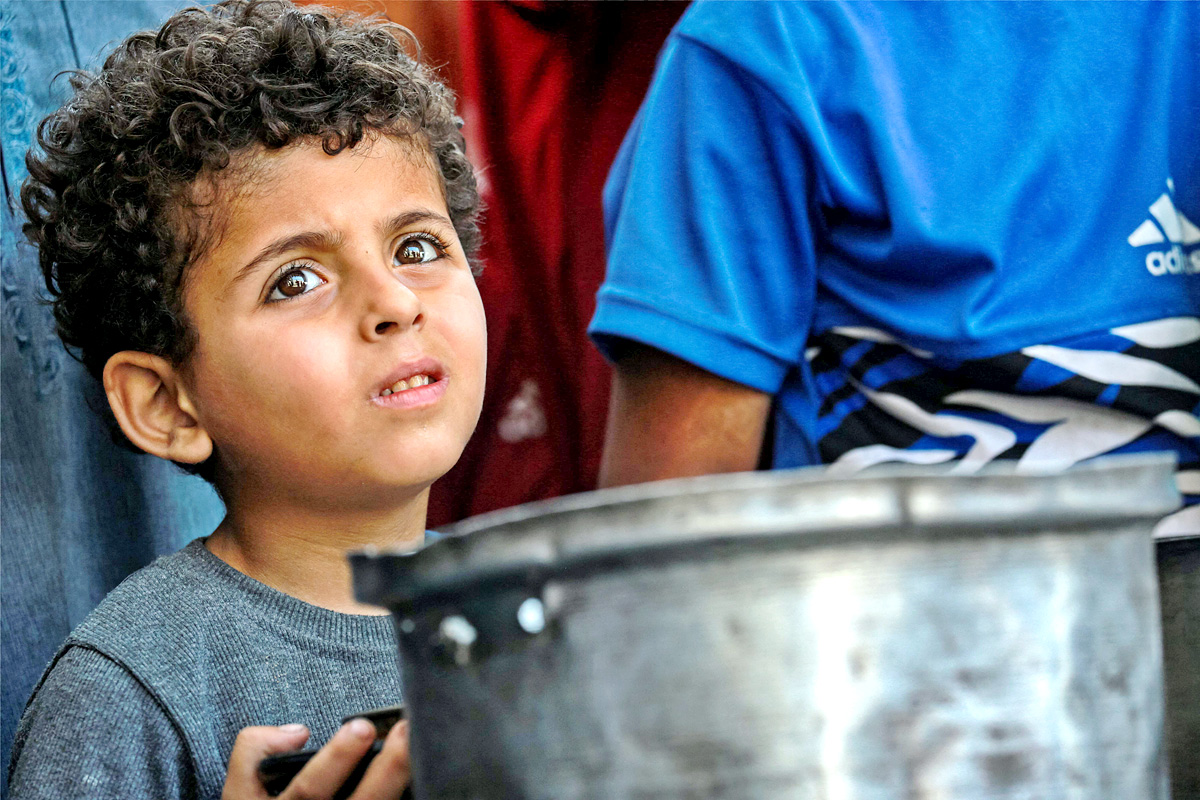 Palestinians wait for donated food at a community kitchen in Gaza City2