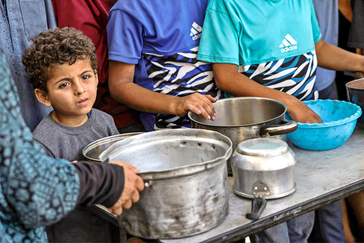 Palestinians wait for donated food at a community kitchen in Gaza City3
