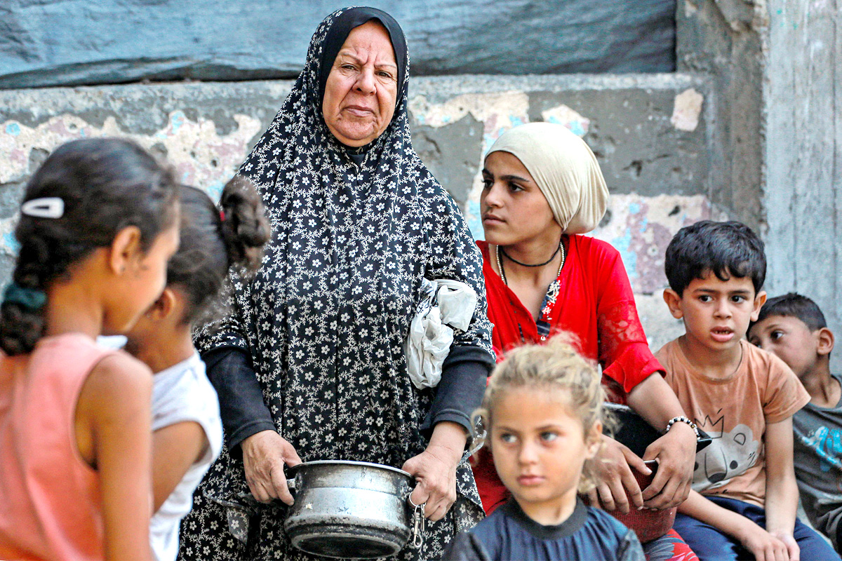Palestinians wait for donated food at a community kitchen in Gaza City4