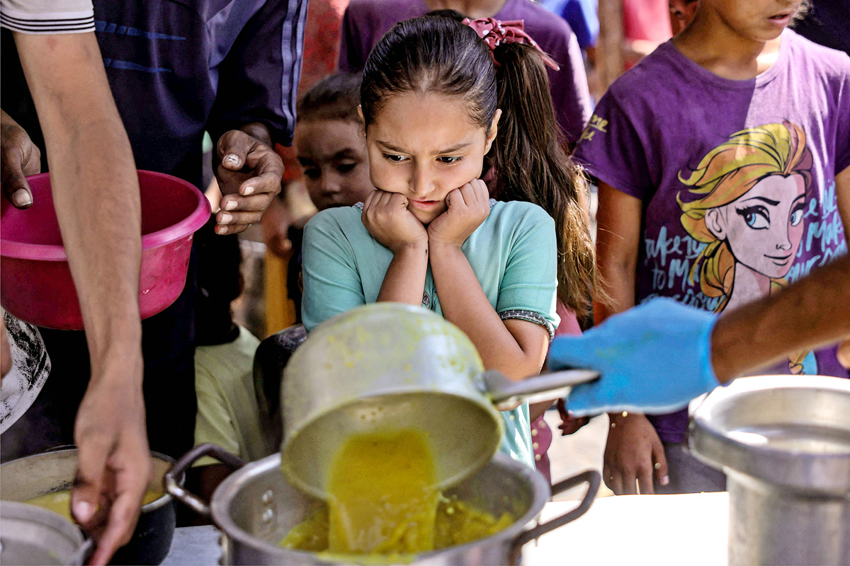 Palestinians wait for donated food at a community kitchen in Gaza City9