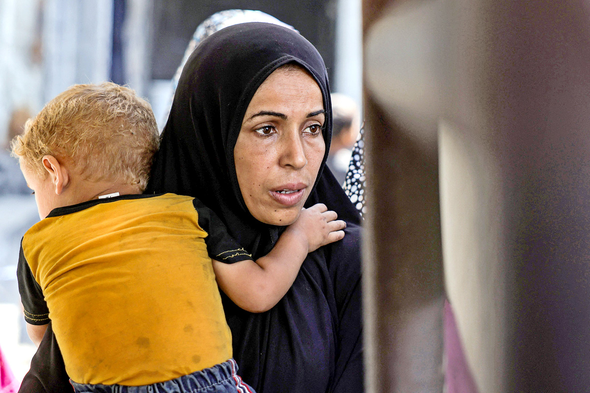 Palestinians wait for donated food at a community kitchen in Gaza City11