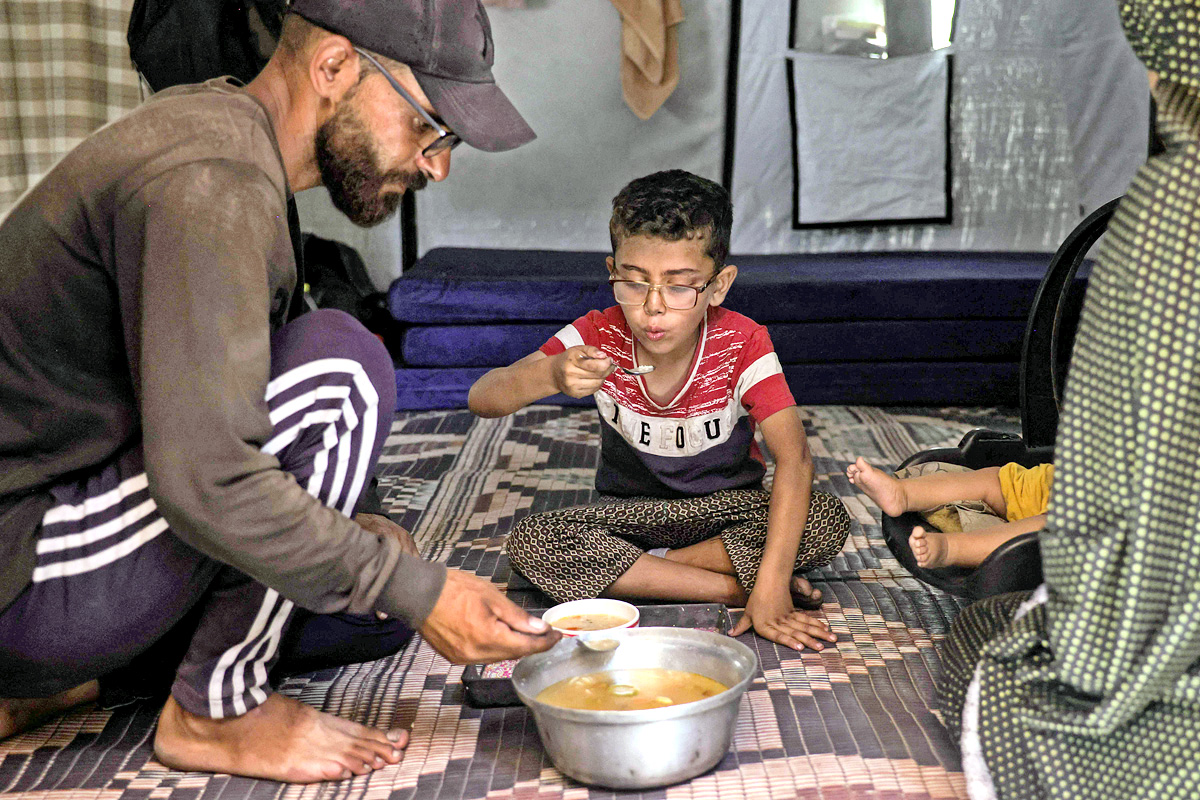 Palestinians wait for donated food at a community kitchen in Gaza City14