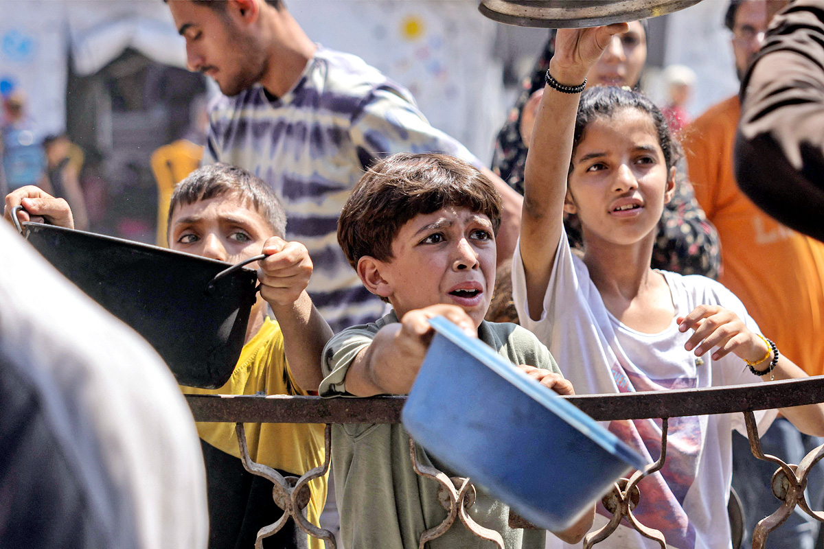 Palestinians wait for donated food at a community kitchen in Gaza City15