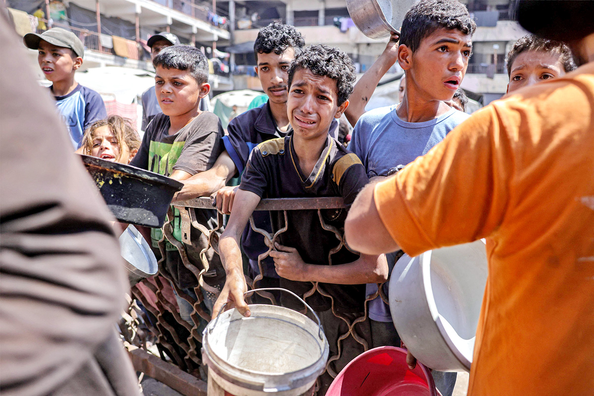 Palestinians wait for donated food at a community kitchen in Gaza City16