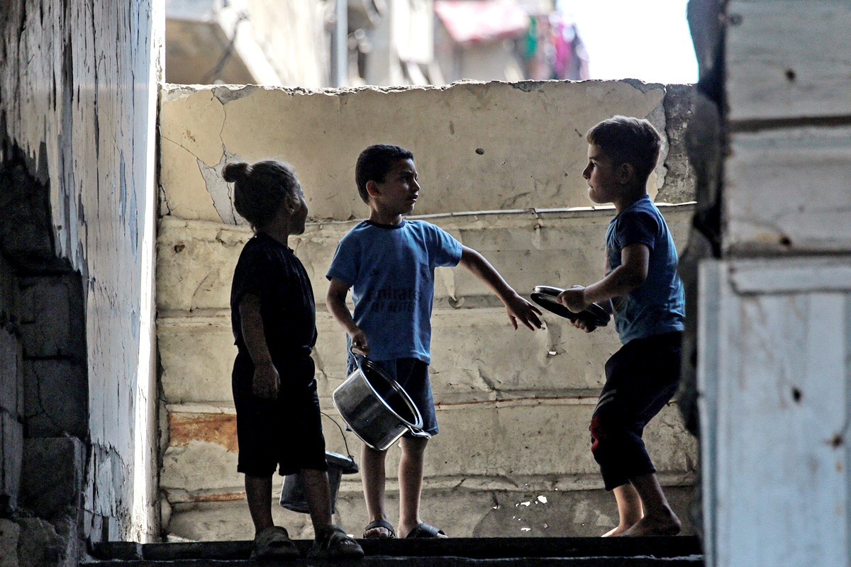 Palestinians wait for donated food at a community kitchen in Gaza City17
