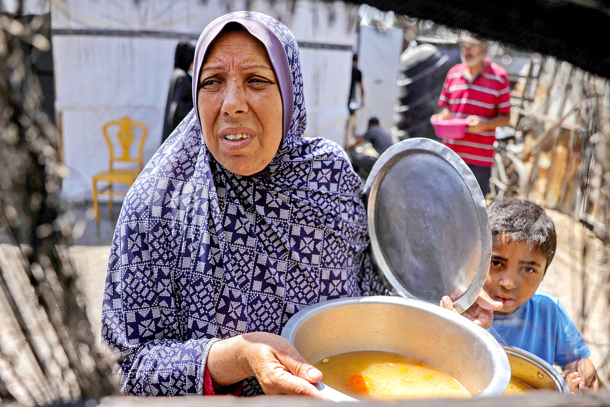 Palestinians wait for donated food at a community kitchen in Gaza City18