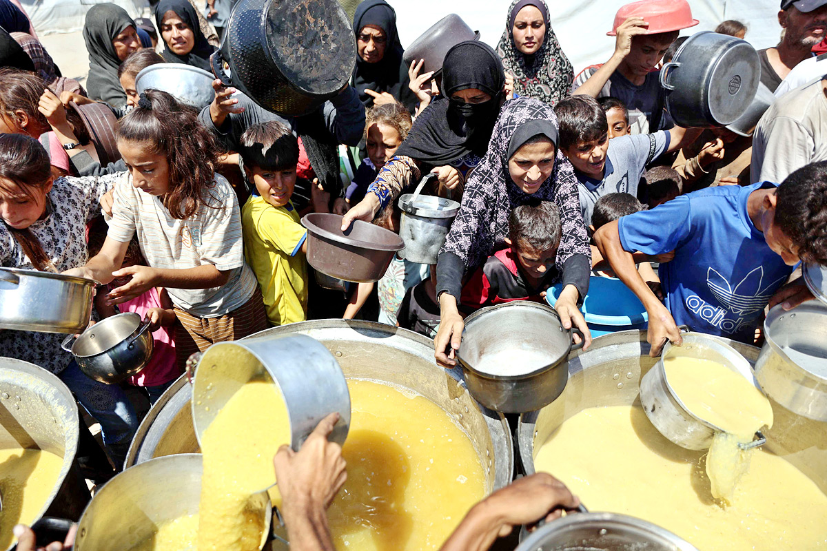 Palestinian boy receives the last drops of lentil soup at a food distribution point in Gaza4