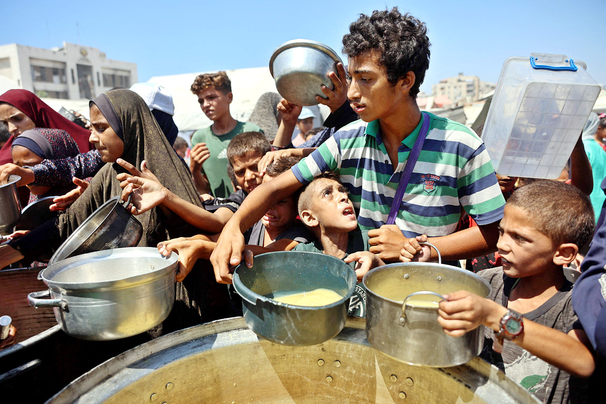 Palestinian boy receives the last drops of lentil soup at a food distribution point in Gaza5