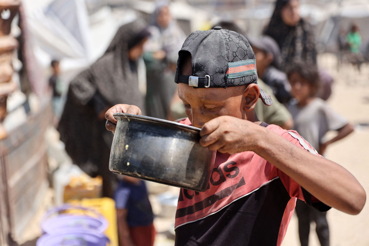 Palestinian boy receives the last drops of lentil soup at a food distribution point in Gaza6