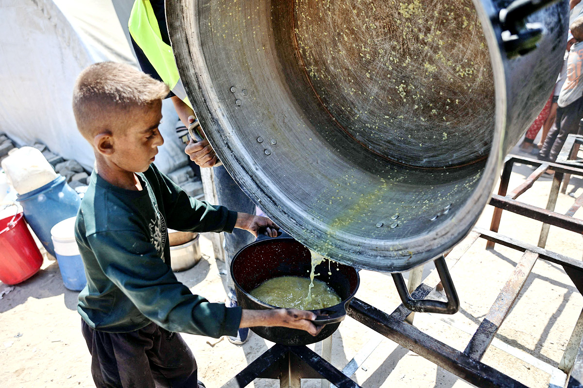 Palestinian boy receives the last drops of lentil soup at a food distribution point in Gaza9