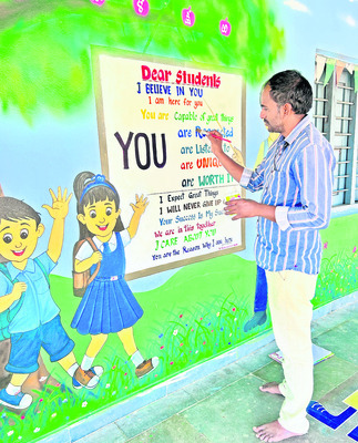 Teacher Vighnavardhan Naidu writing words on the walls at Nagarala school2