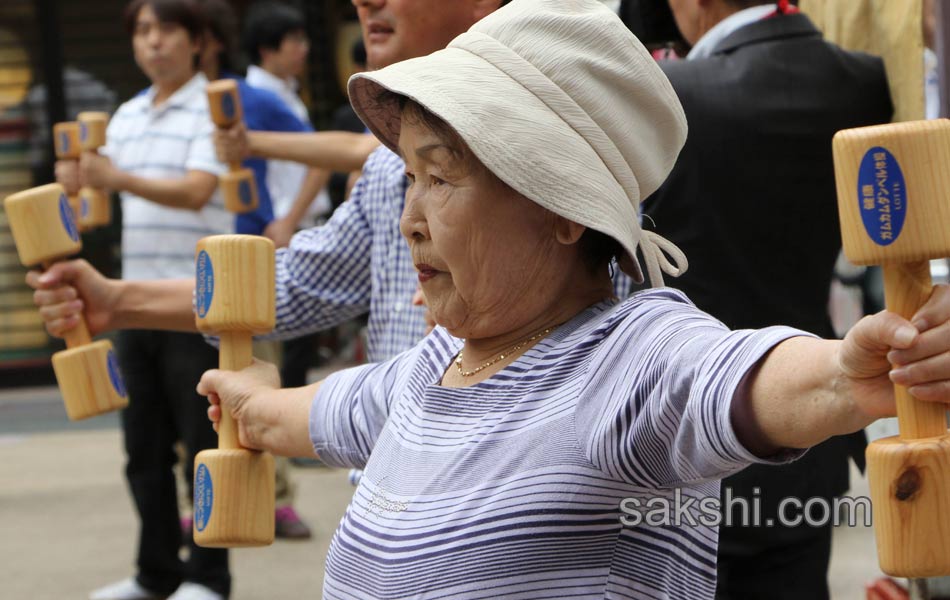Elderly people work out with wooden dumb bells