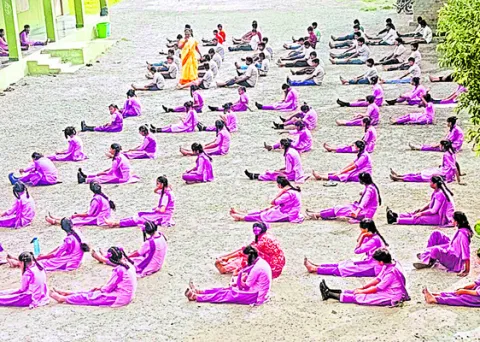 మండుటెండలో కటిక నేలపై  విద్యార్థుల యోగాసనాలు 