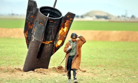 A shepherd boy walks away from an unexploded Iranian projectile that landed